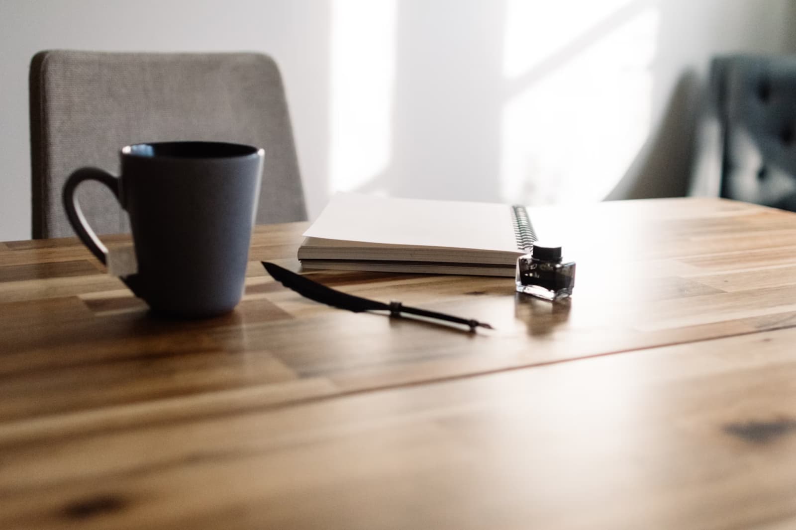 A serene workspace with a mug, notebook, and pen on a wooden table.