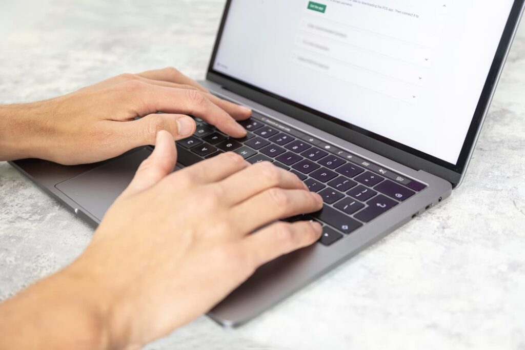 Hands typing on a laptop with a web form on the screen.