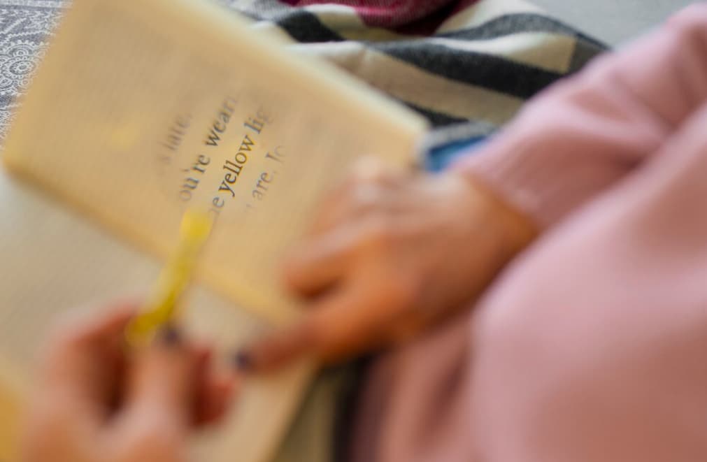 A person highlighting text in a blurry book photo.